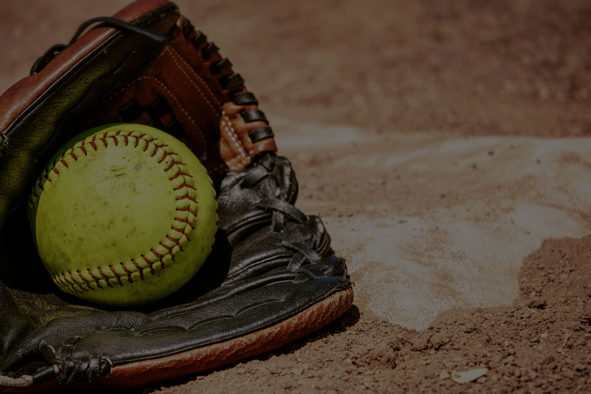 Softball and glove in front of the base.